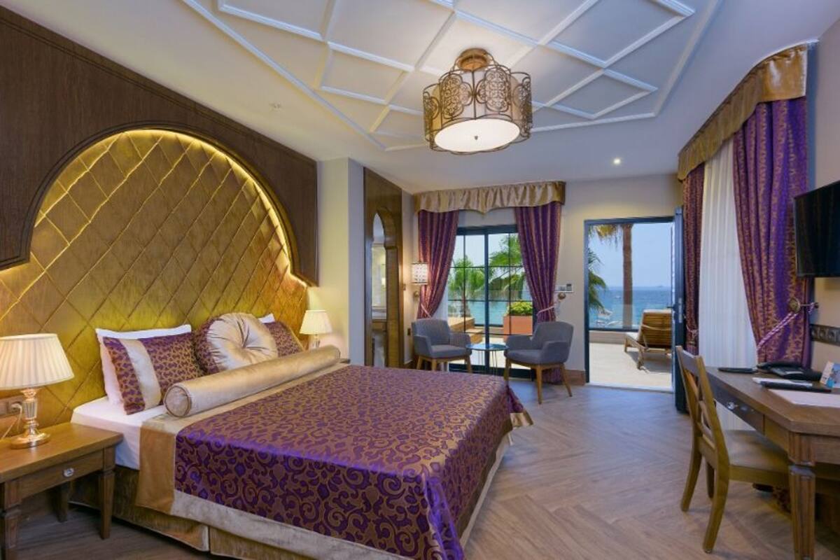 Ein geräumiges Schlafzimmer mit einem großen Bett, einer Duschkabine aus Glas und Blick aufs Meer.