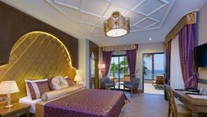 A hotel room with a large bed, a desk, and a view of the ocean.