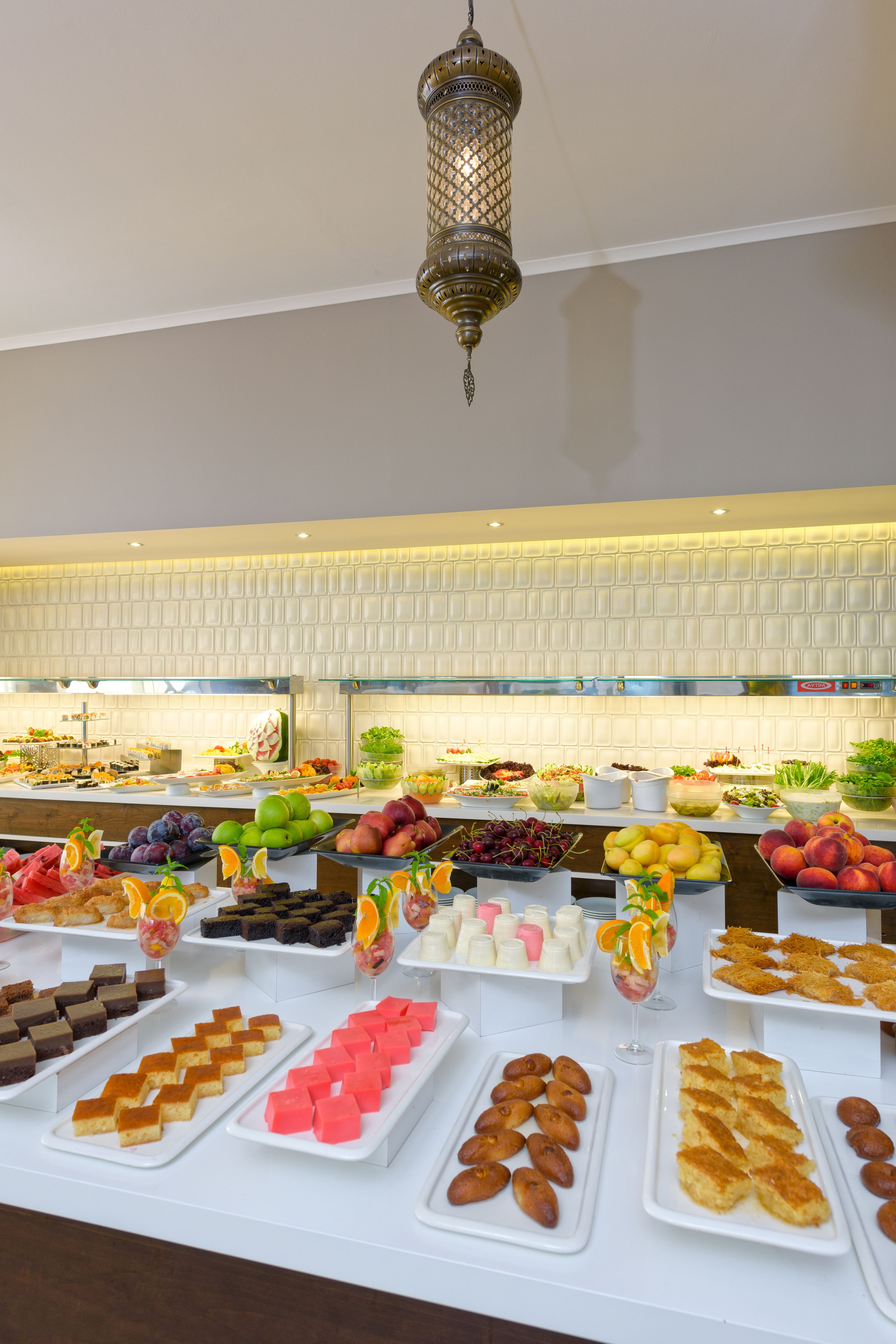 A buffet with various food items and a decorative hanging light fixture.