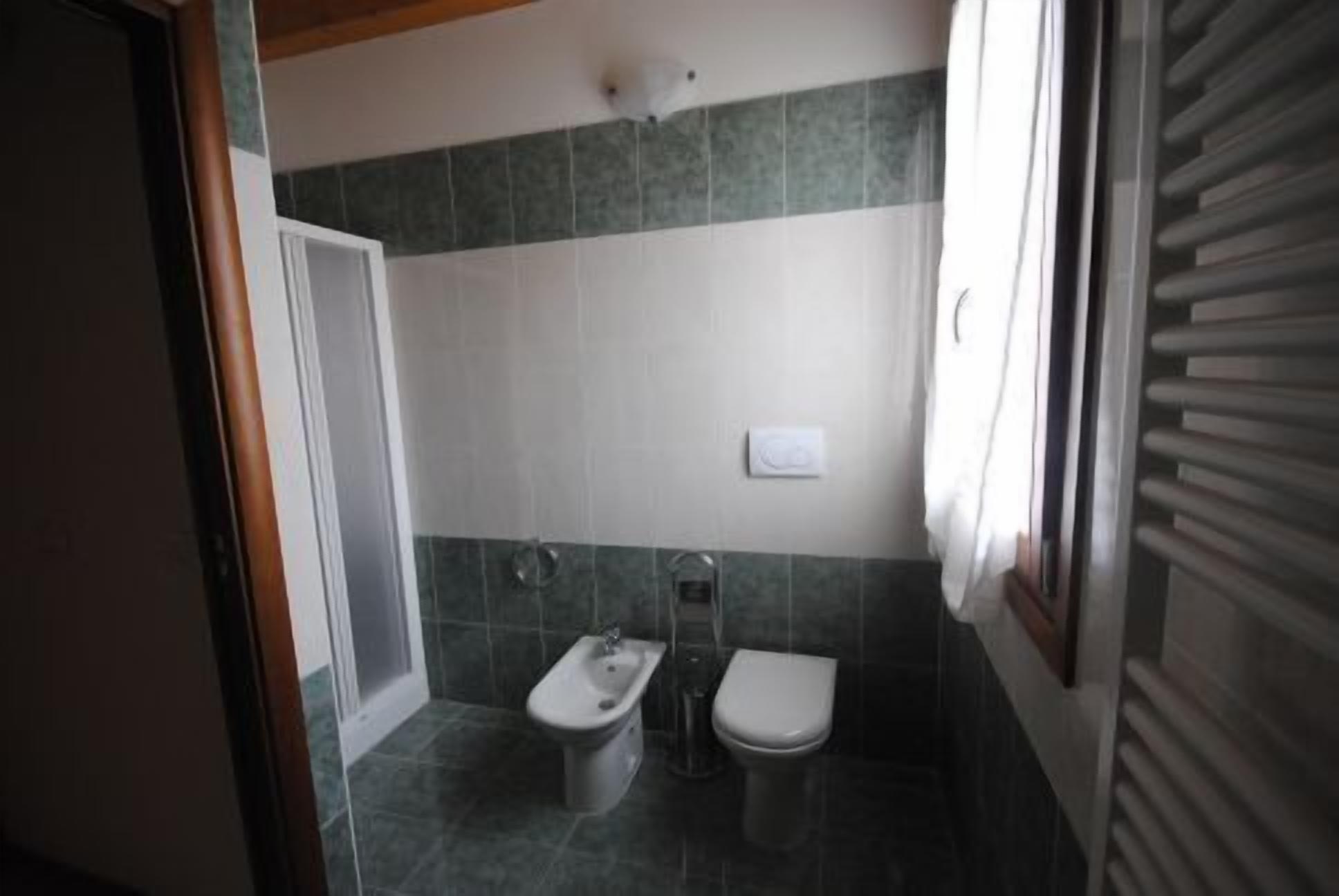 Une petite salle de bain équipée d’un bidet, de toilettes et d’un lavabo.