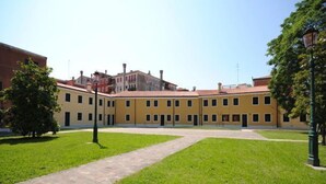 Une cour avec un bâtiment jaune, des allées pavées et des arbres.
