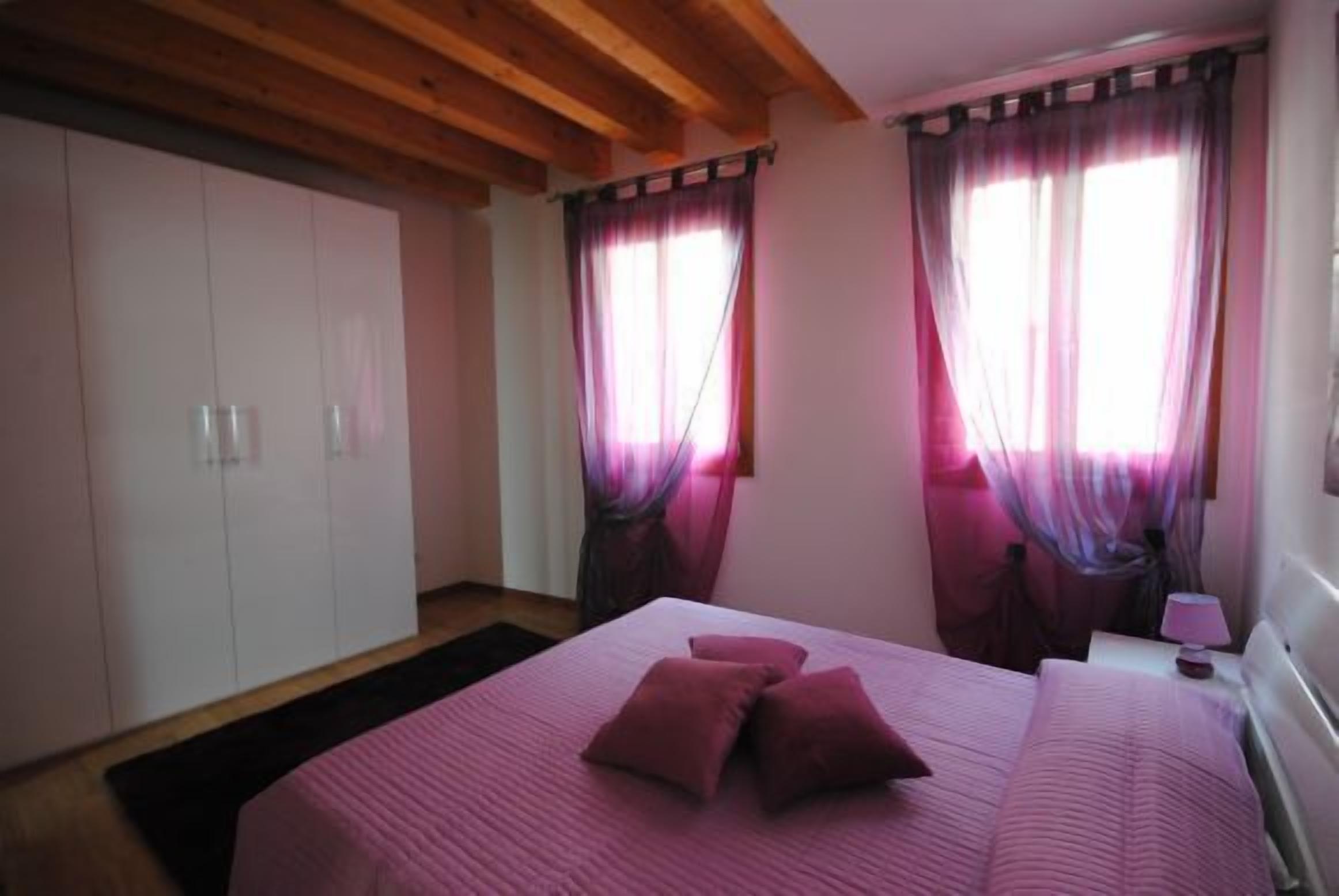 A bedroom with a bed, two bedside tables, a wardrobe, and curtains.