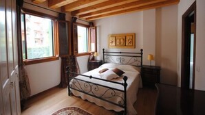 Une chambre à coucher avec un plafond en bois, un lit avec un cadre en métal, une table de chevet avec une lampe et une fenêtre avec des rideaux.