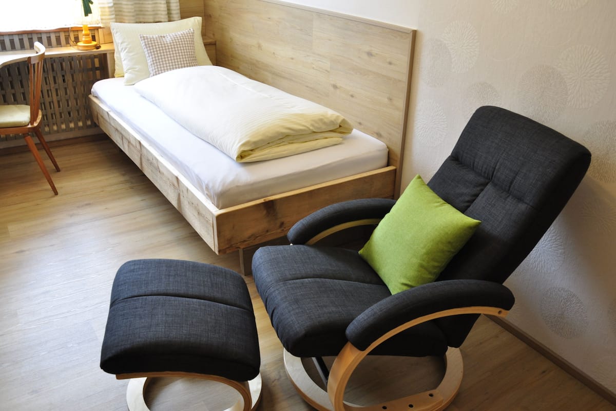 Un dormitorio con cama de madera, un escritorio, una silla y una mesita.