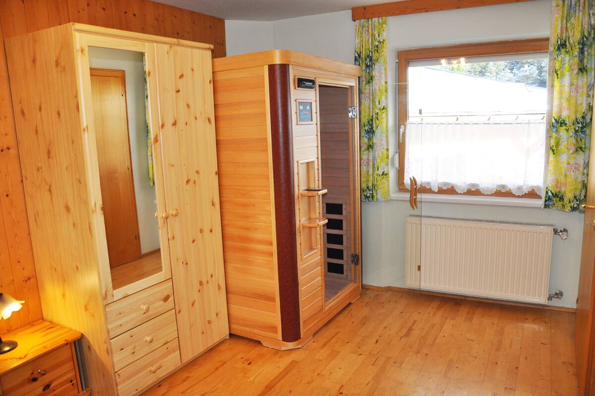 A wooden room with a sauna, a window with curtains, and a radiator.