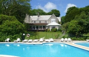 A large swimming pool with white lounge chairs and a gazebo.