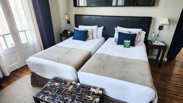 A double bed room with two bedside tables, a nightstand, a bench, and a large mirror on the wall.