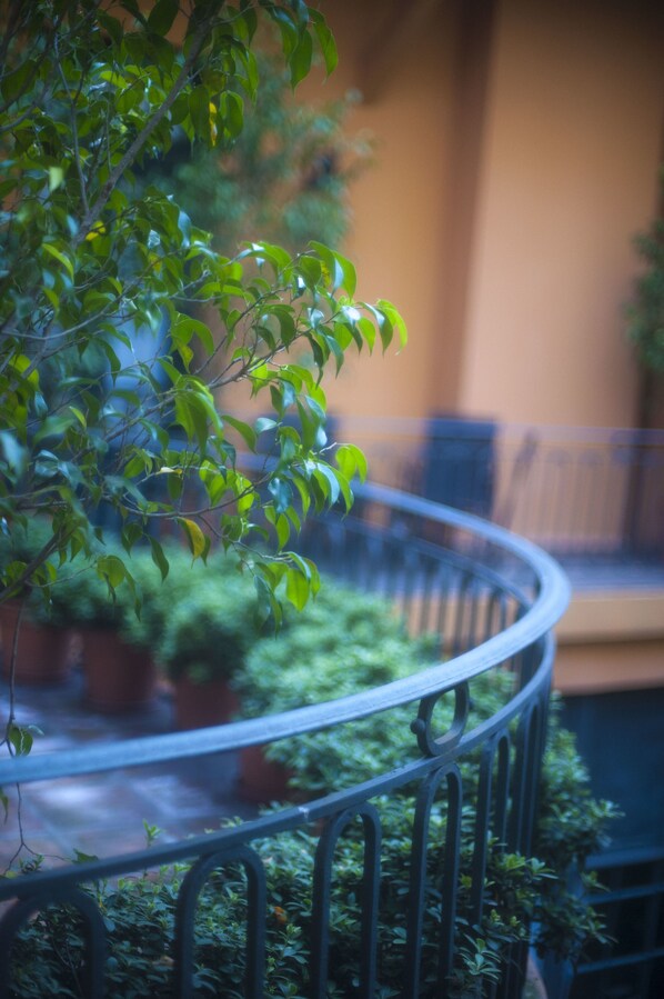 A curved metal railing with a potted plant and greenery in the foreground.