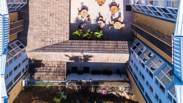 Une cour dotée d’un espace extérieur aménagé, entourée d’immeubles à plusieurs étages avec des balcons.