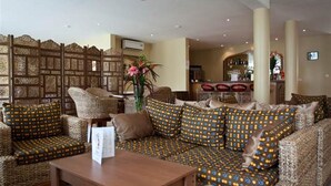 Un coin salon accueillant, avec des canapés et des fauteuils à motifs, une table basse en bois et un panneau décoratif mural.