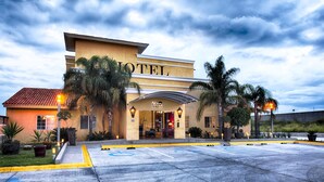 Un hotel con estacionamiento, palmeras y cielo despejado.