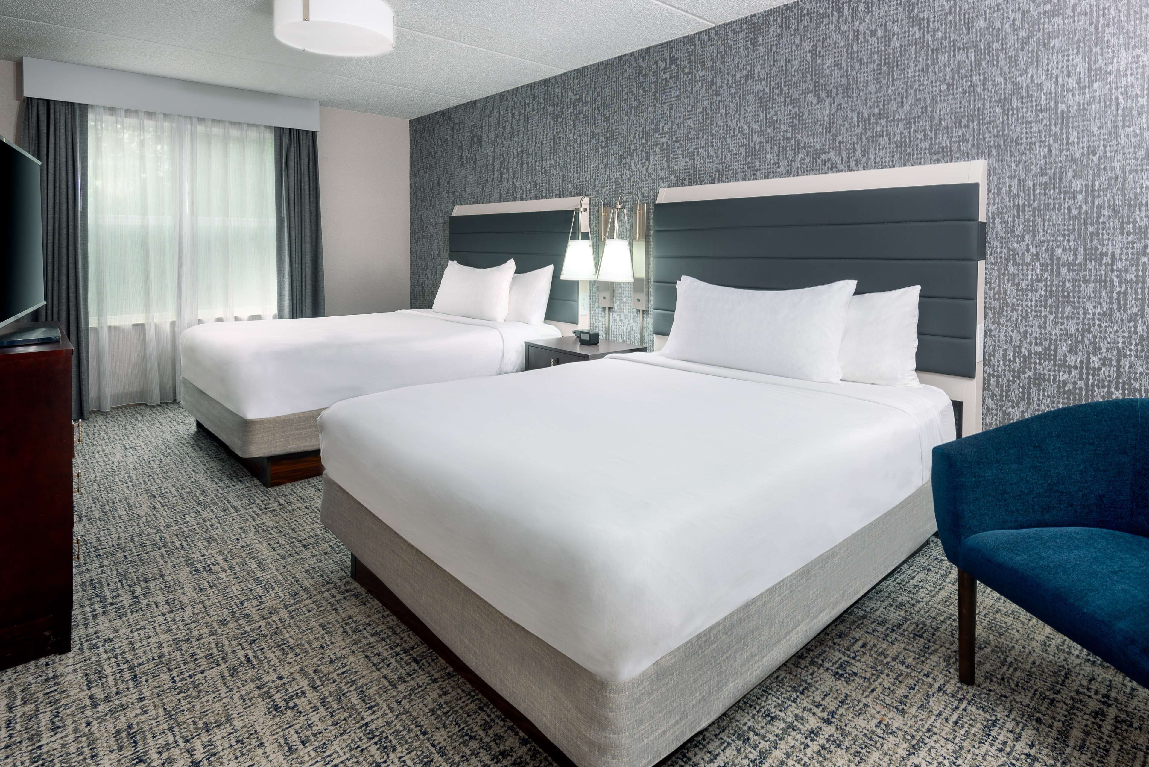 Une chambre d’hôtel avec deux lits, une télévision, un bureau, une lampe et une chaise.