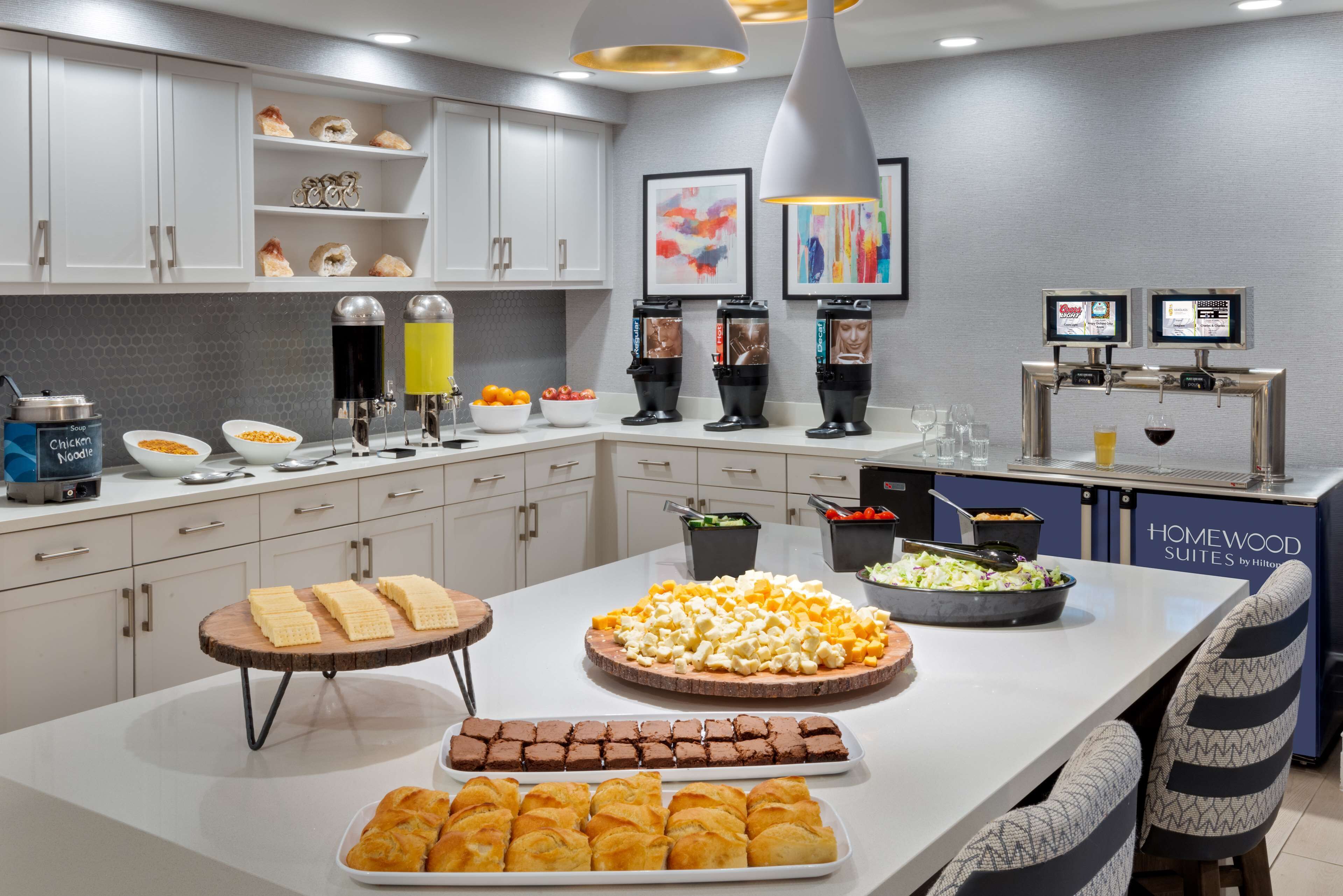 A modern kitchen with a buffet setup, including various food items and a coffee station.