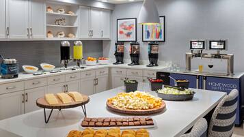 A modern kitchen with a buffet setup, including various food items and a coffee station.