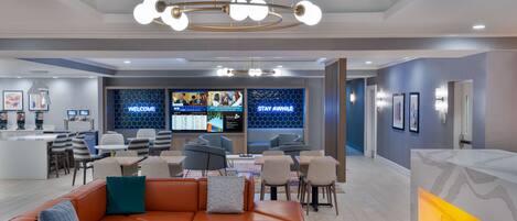 A modern lobby with a reception desk, seating area, and a large digital display.