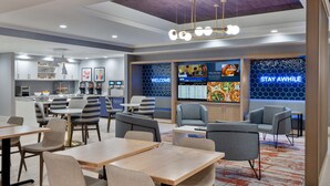 A modern hotel lobby with a reception desk, seating area, and a large digital menu board. - Homewood Suites by Hilton Boston/Canton, MA (Canton)