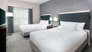 A hotel room with two beds, a TV, a desk, and a lamp.