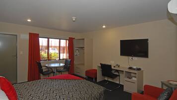 A hotel room with a bed, a desk, a chair, a television, and a window with curtains.