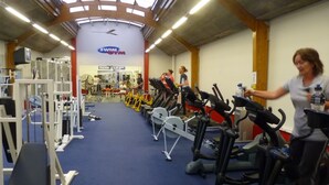 Un gimnasio con cintas de correr, bicicletas estáticas y máquinas de pesas.