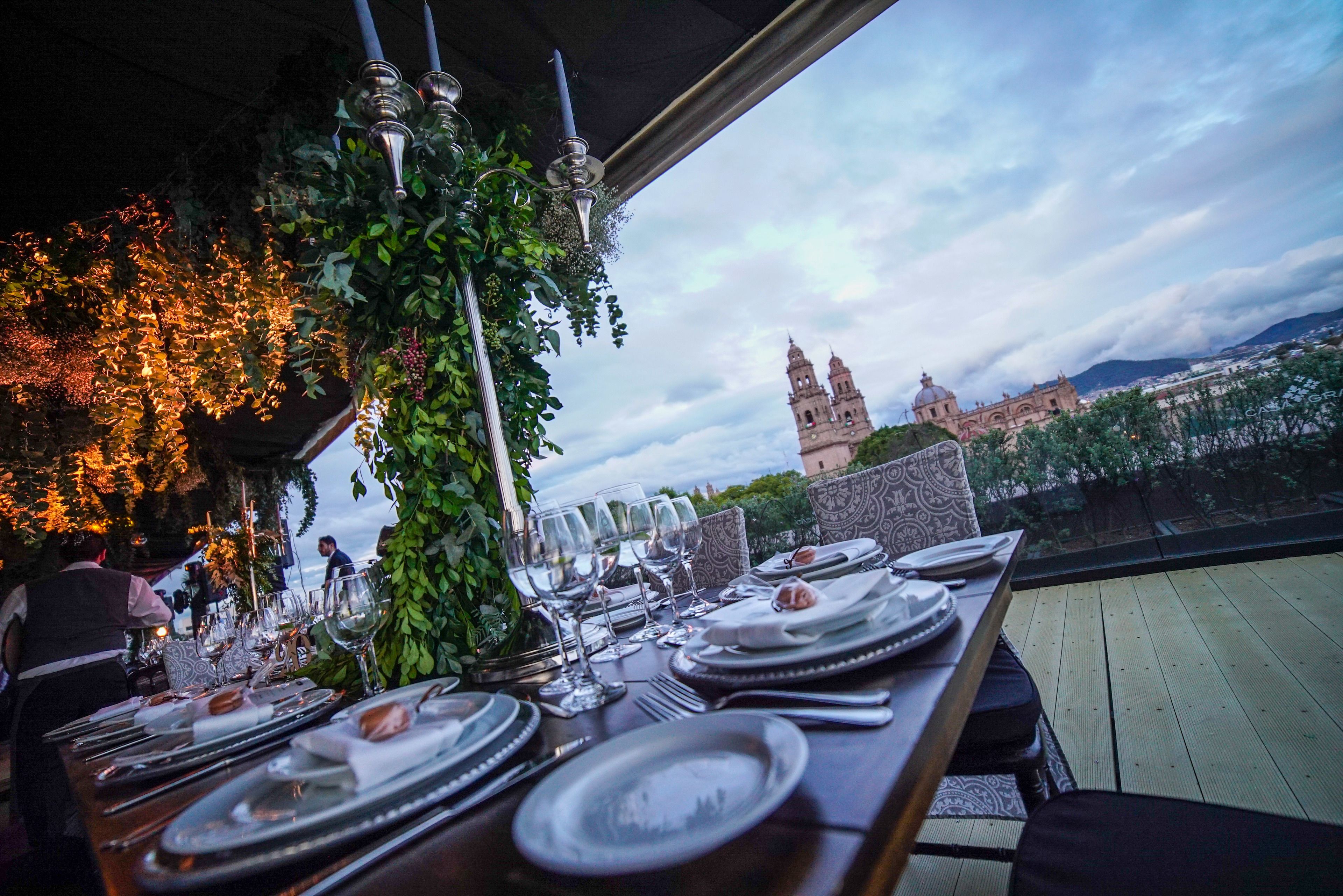 A dining table set with plates, glasses, and cutlery, overlooking a historic building with towers.