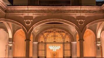 Um edifício com uma entrada central em arco, uma varanda com guarda-corpo e a lua no céu.