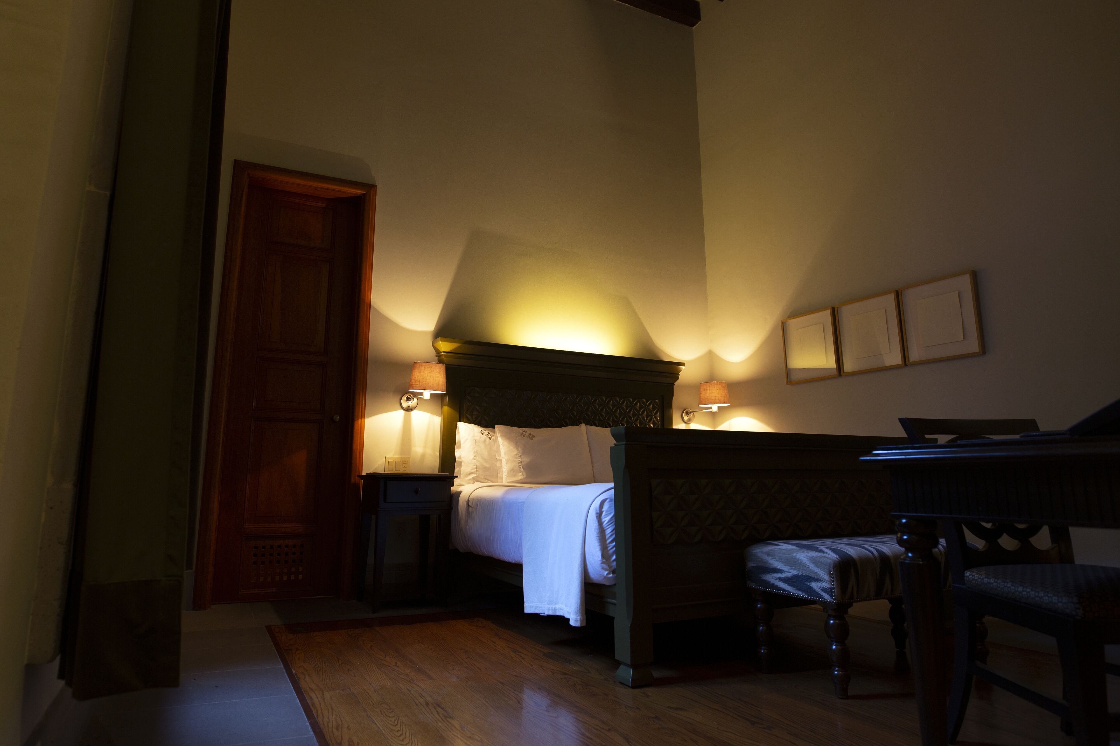 A bedroom with a bed, bedside tables, a chair, and a wooden floor.