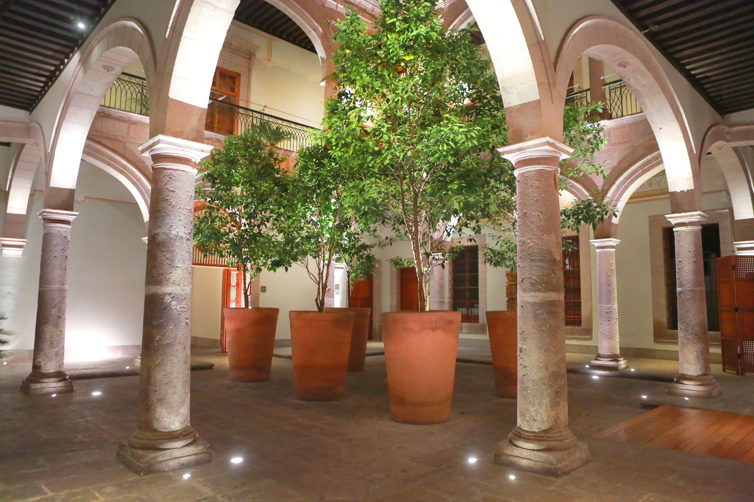 A spacious courtyard with large terracotta planters and classical columns.
