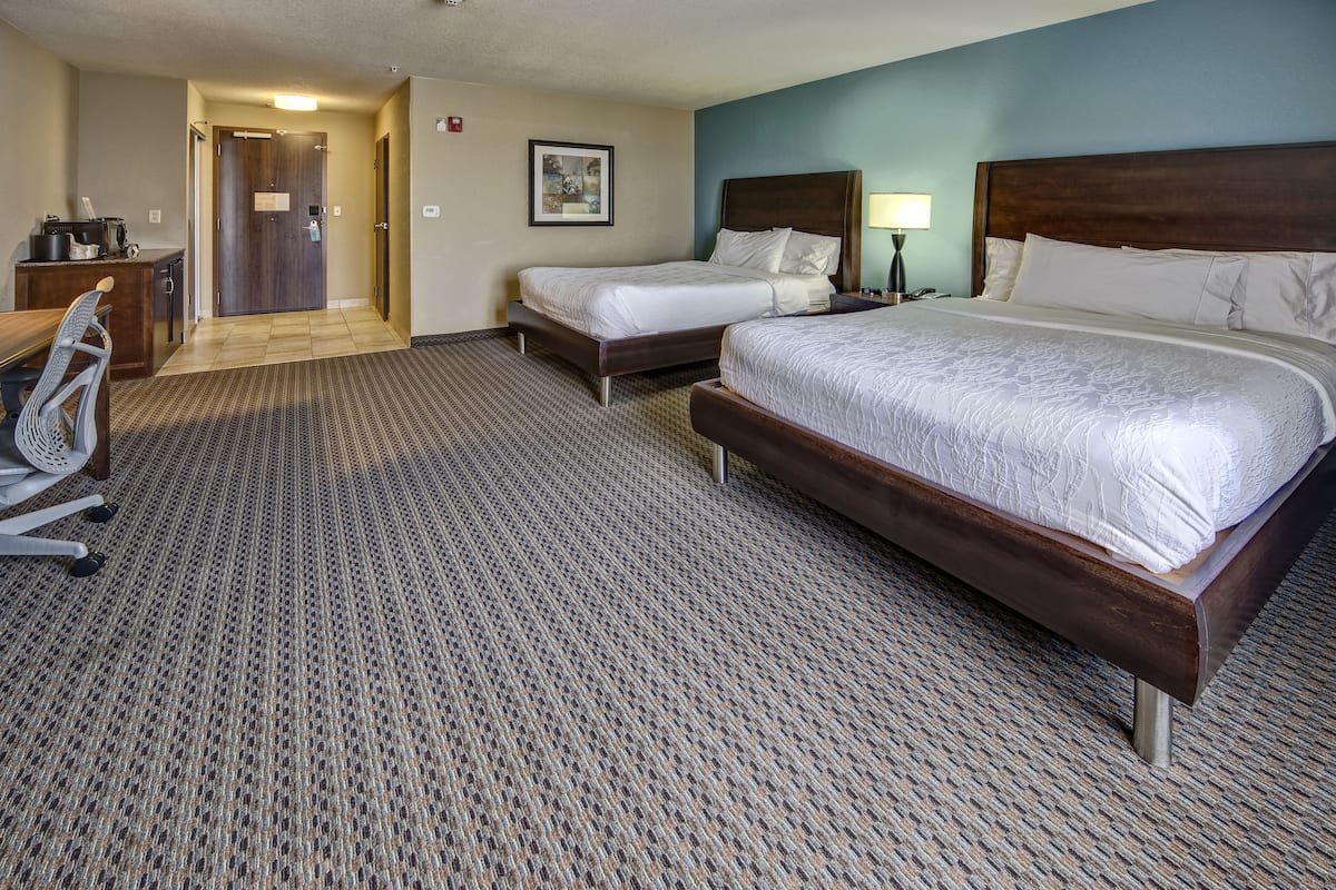 A hotel room with two beds, a desk, and a chair.