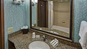 A bathroom with a granite countertop, a white sink, a mirror, a towel rack, and a shower curtain.