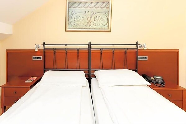 A double bed with a wooden headboard, bedside tables with lamps, and a wall-mounted artwork.