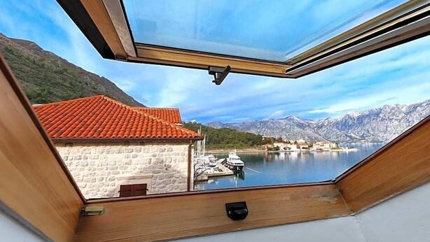 Een kamer met uitzicht op een meer, bergen en een gebouw met een rode dakbedekking.