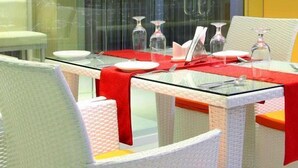 Een eettafel met glazen blad en witte stoelen, gedekt met borden, glazen en bestek.