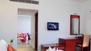 Hotelkamer met een bed, bureau, stoel, televisie en een badkamer zichtbaar door een geopende deur.