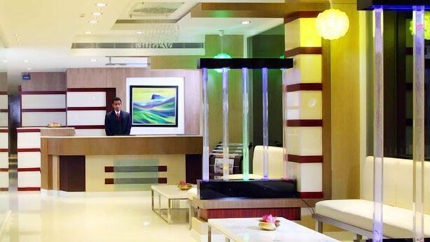 Een moderne hotel lobby met een receptiebalie, zithoek en kunstwerken aan de muren.