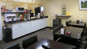 A small hotel room with a kitchenette, a dining area with a table and chairs, and a single bed. - Super 8 by Wyndham Saskatoon Near Downtown (Saskatoon)