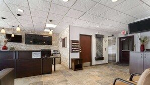 A reception area with a check-in desk, a clock, a television, and an elevator. - Super 8 by Wyndham Saskatoon Near Downtown (Saskatoon)