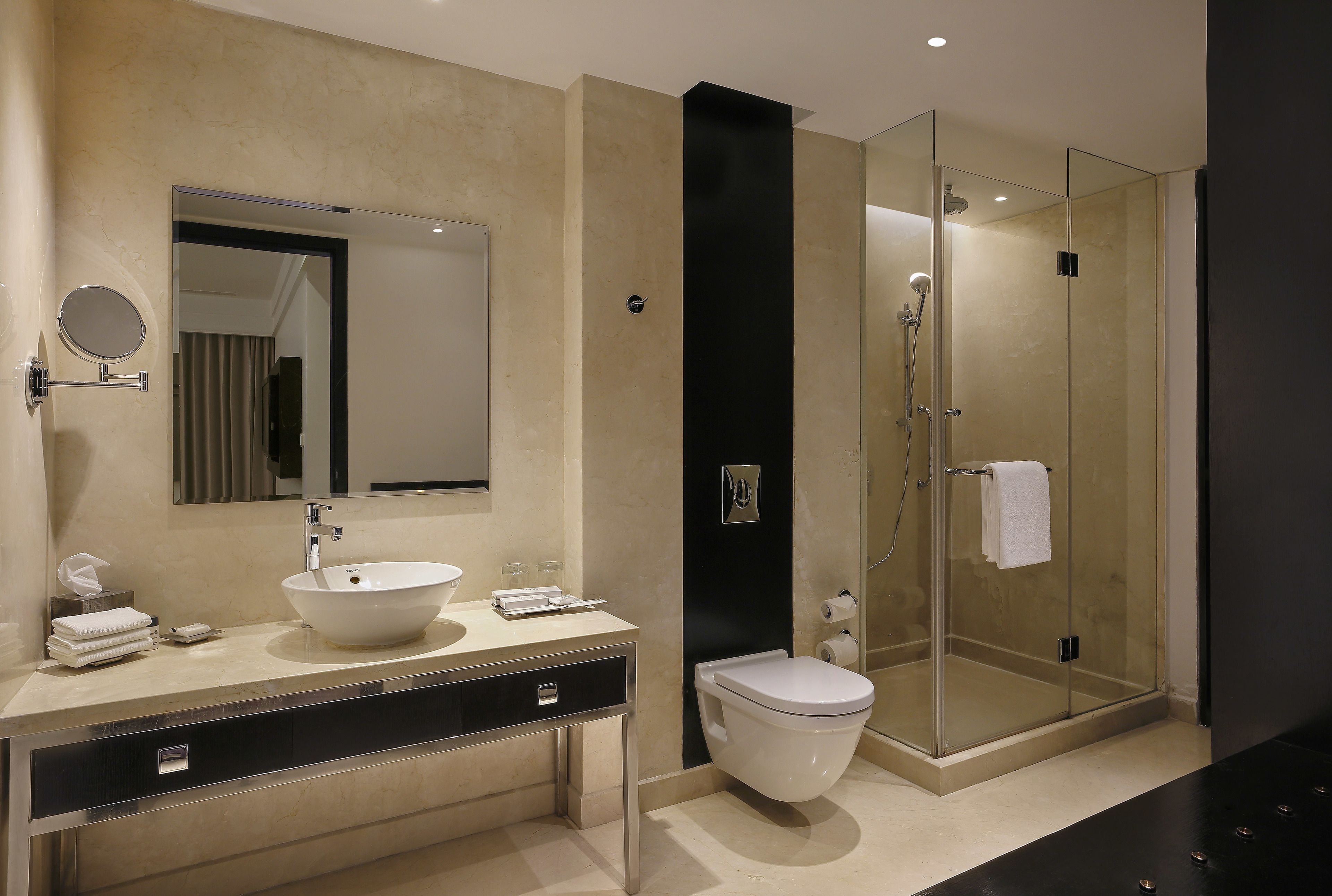 A modern bathroom with a large sink, mirror, toilet, and glass-enclosed shower.
