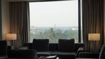 A modern hotel room with a large window, a sofa, two lamps, and a coffee table.