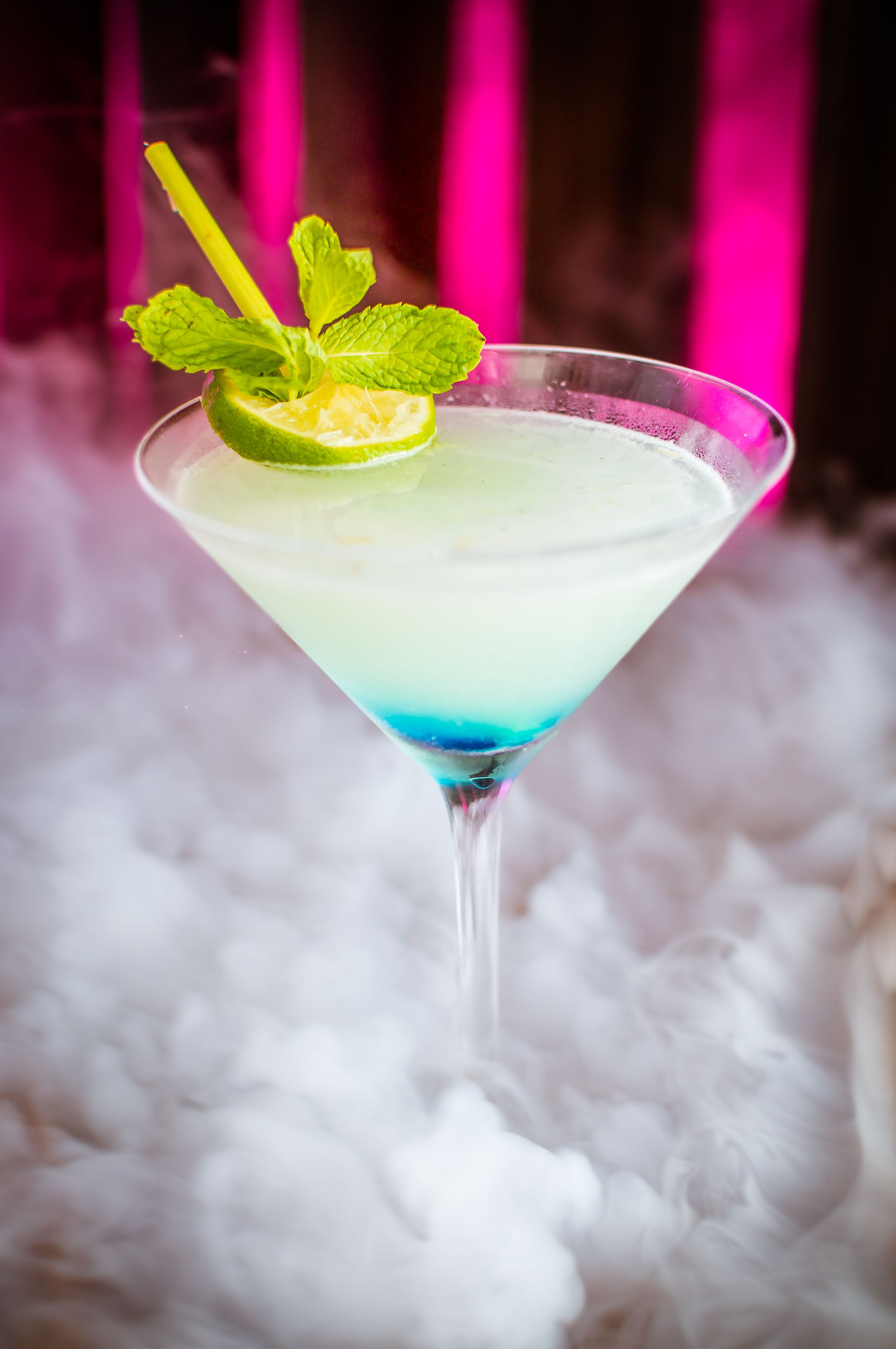 Un got de martini amb una llesca de llimona i una guarnició de menta sobre una superfície blanca i esponjosa.