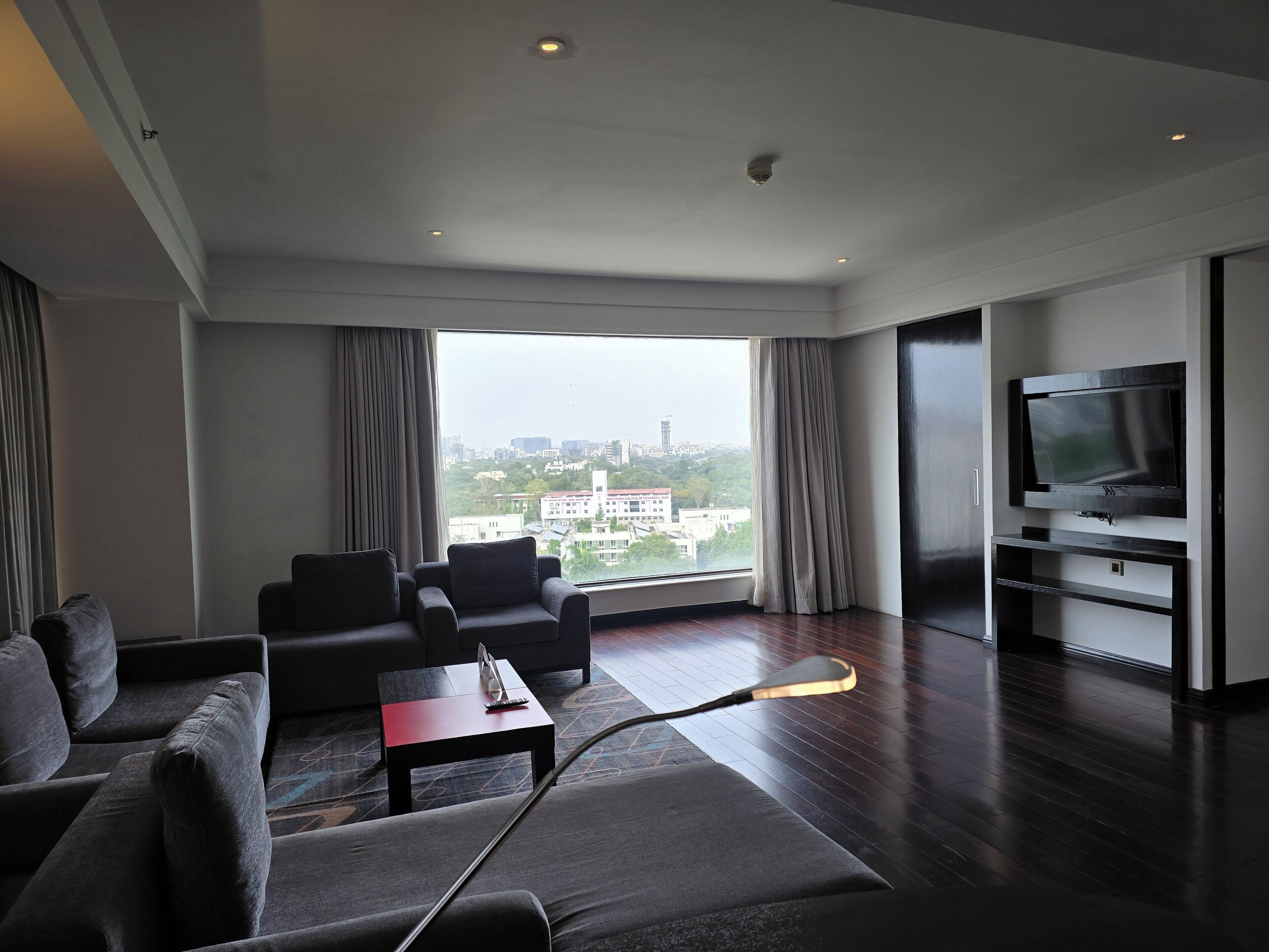 A modern living room with a large window, a flat-screen TV, and a sofa.