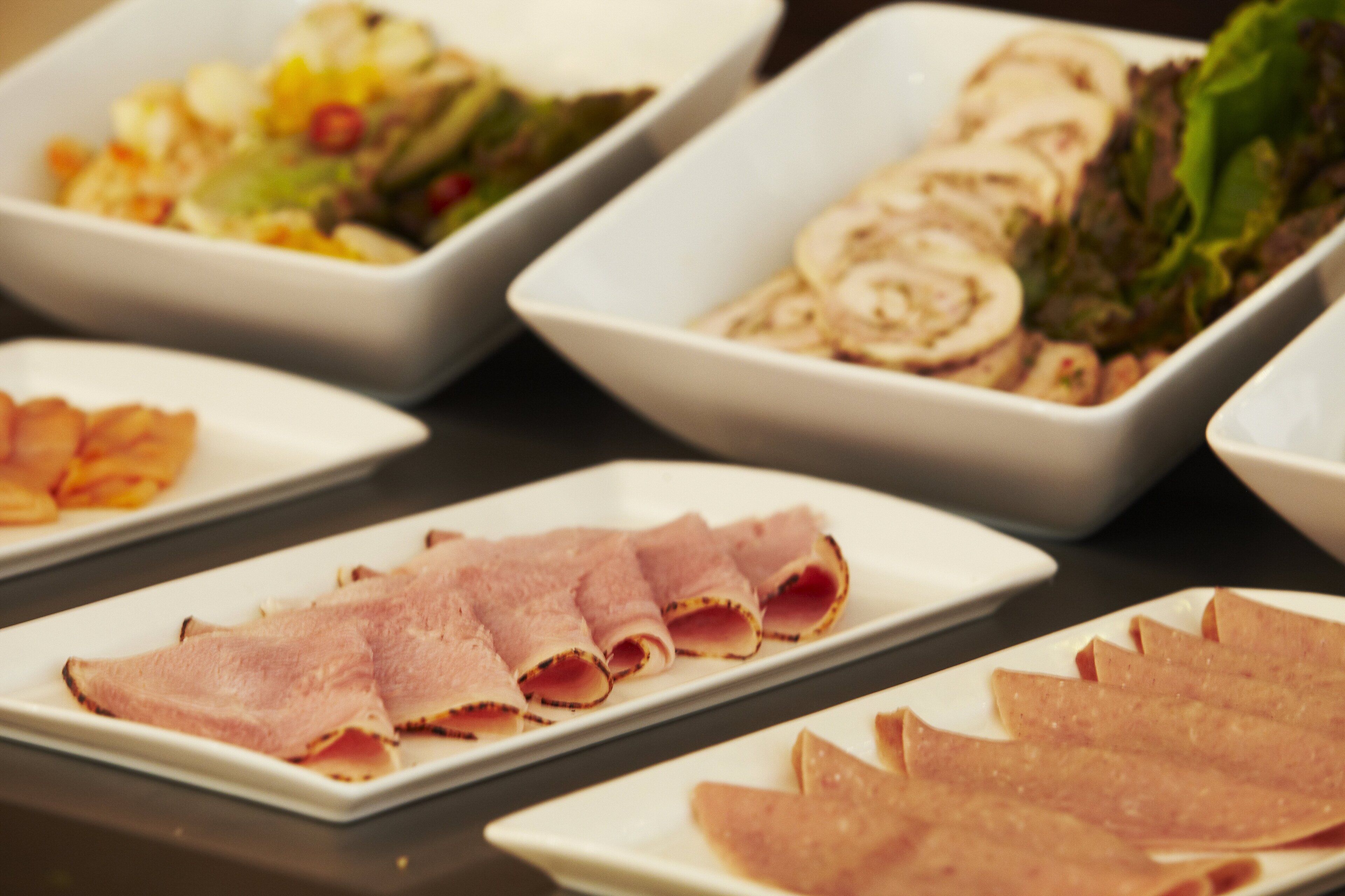 Ein reichhaltiges Buffet mit verschiedenen Speisen, darunter Aufschnitt und Salate.