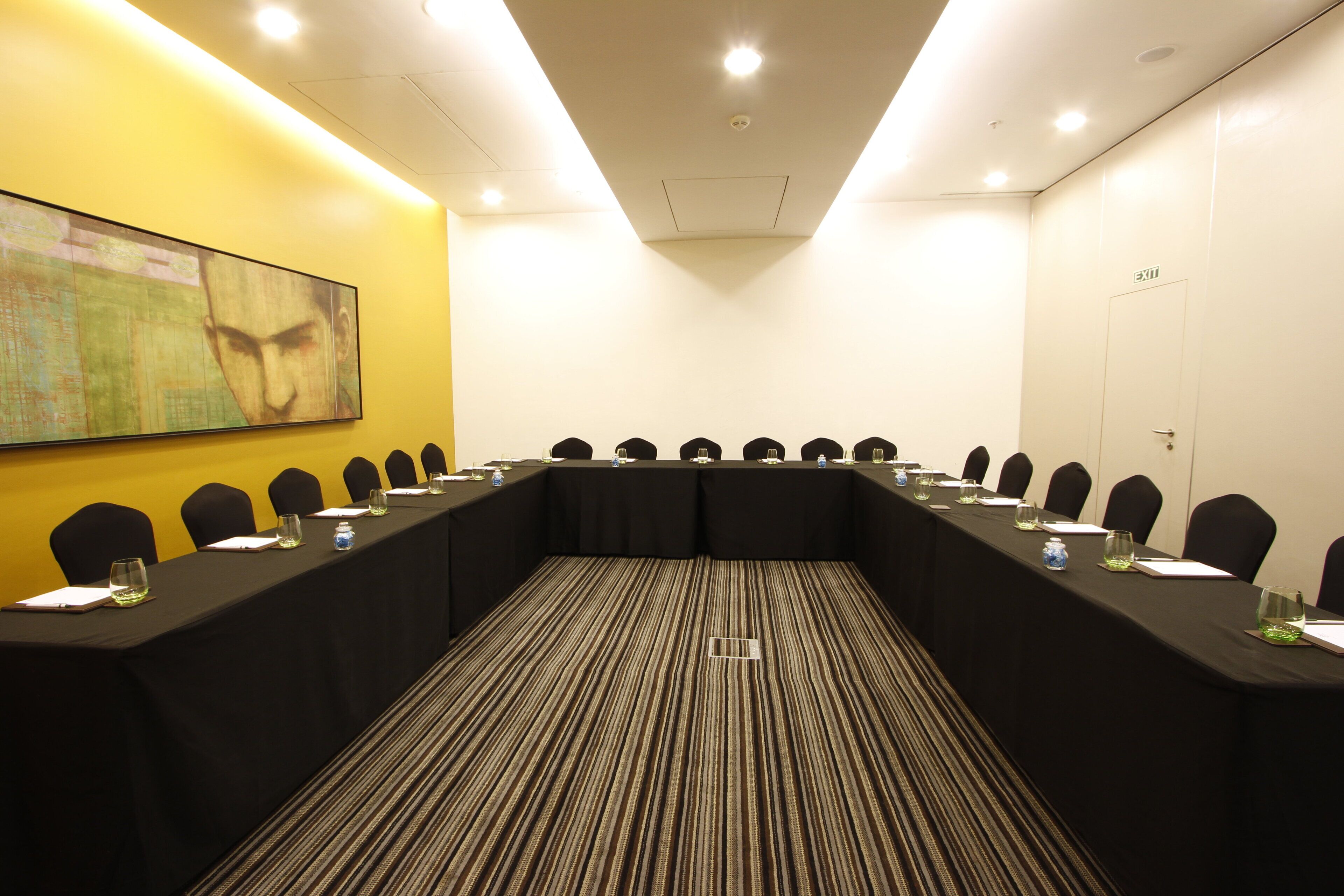 A conference room with a long table, chairs, and a carpeted floor.