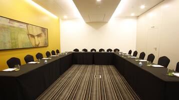 A conference room with a long table, chairs, and a carpeted floor.