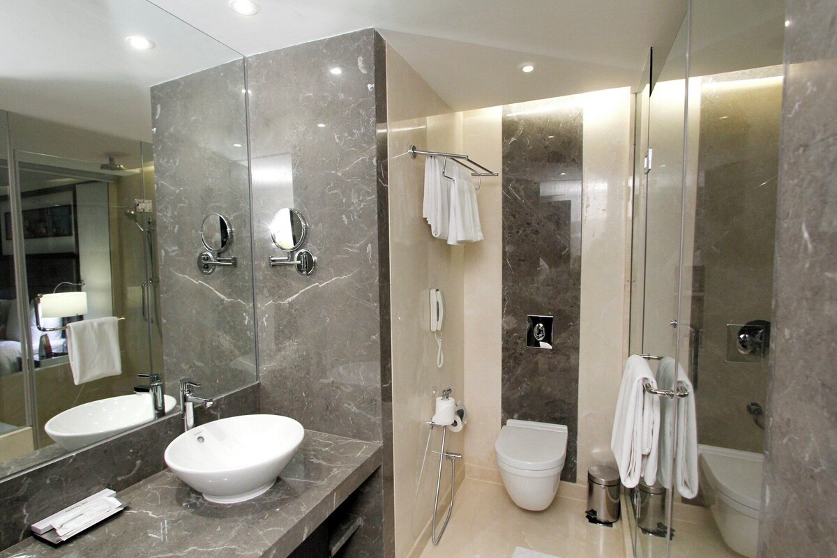 Une salle de bain moderne avec un grand miroir, un lavabo, des toilettes et un espace douche.