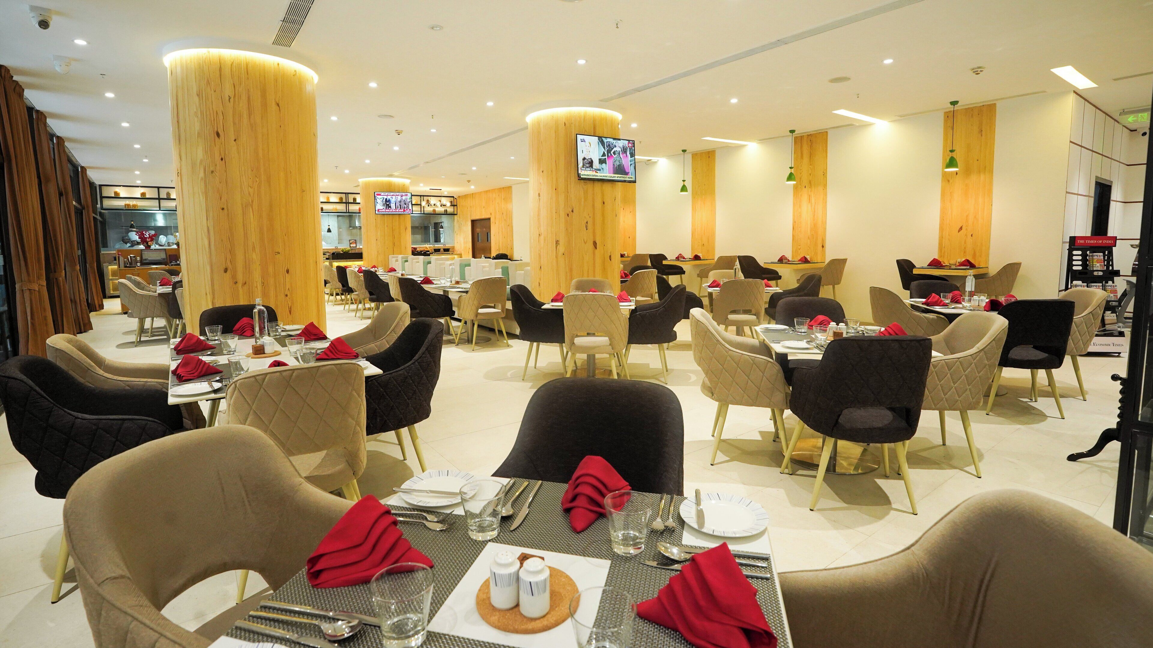 A modern dining area with multiple tables and chairs, wooden accents, and a television screen.