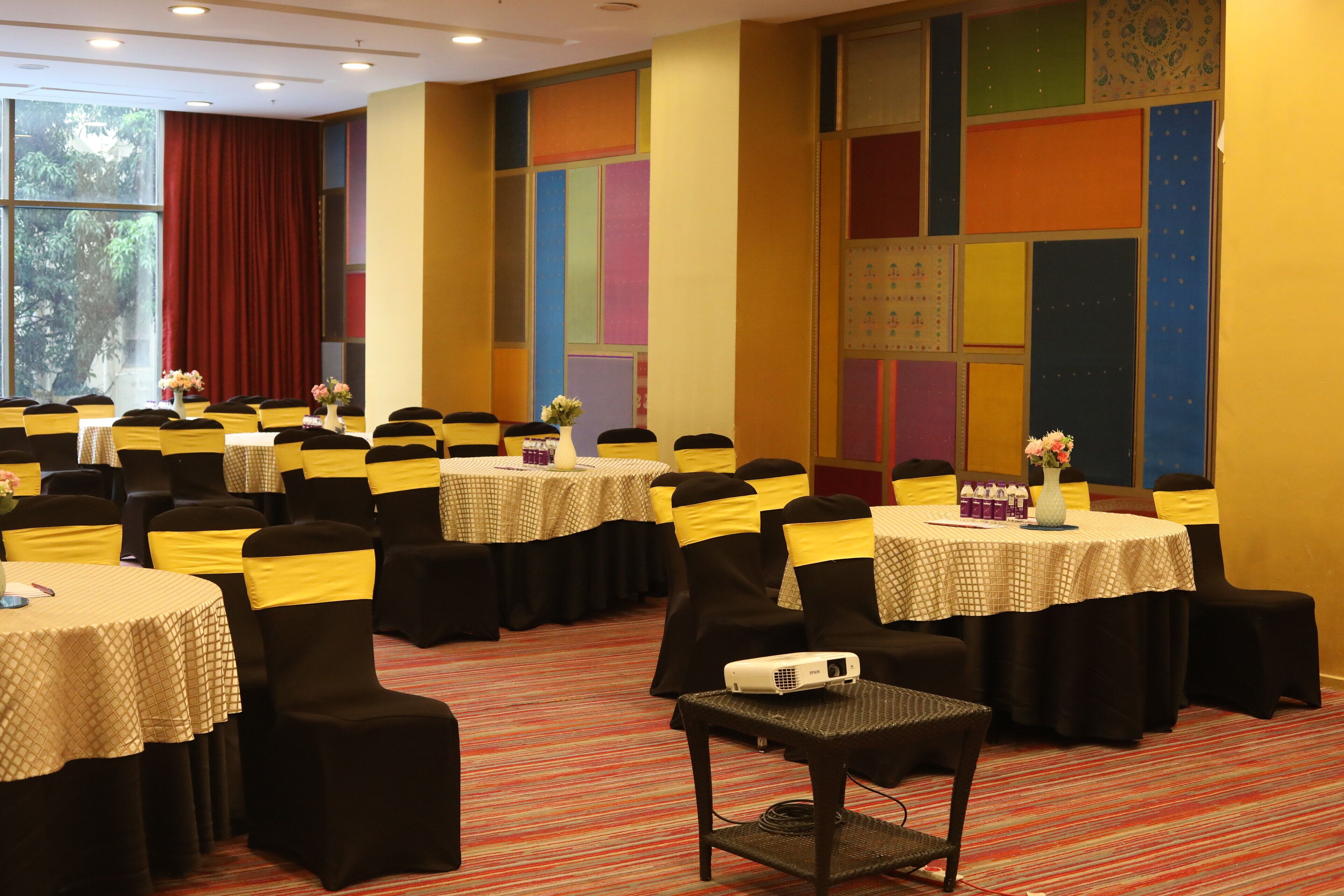 Un salón de conferencias con varias mesas, sillas y un proyector.