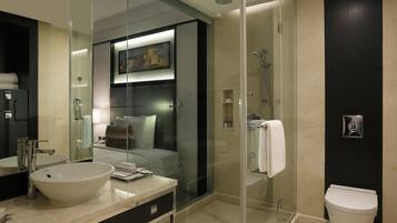 A modern bathroom with a glass-enclosed shower, a large sink, and a toilet.