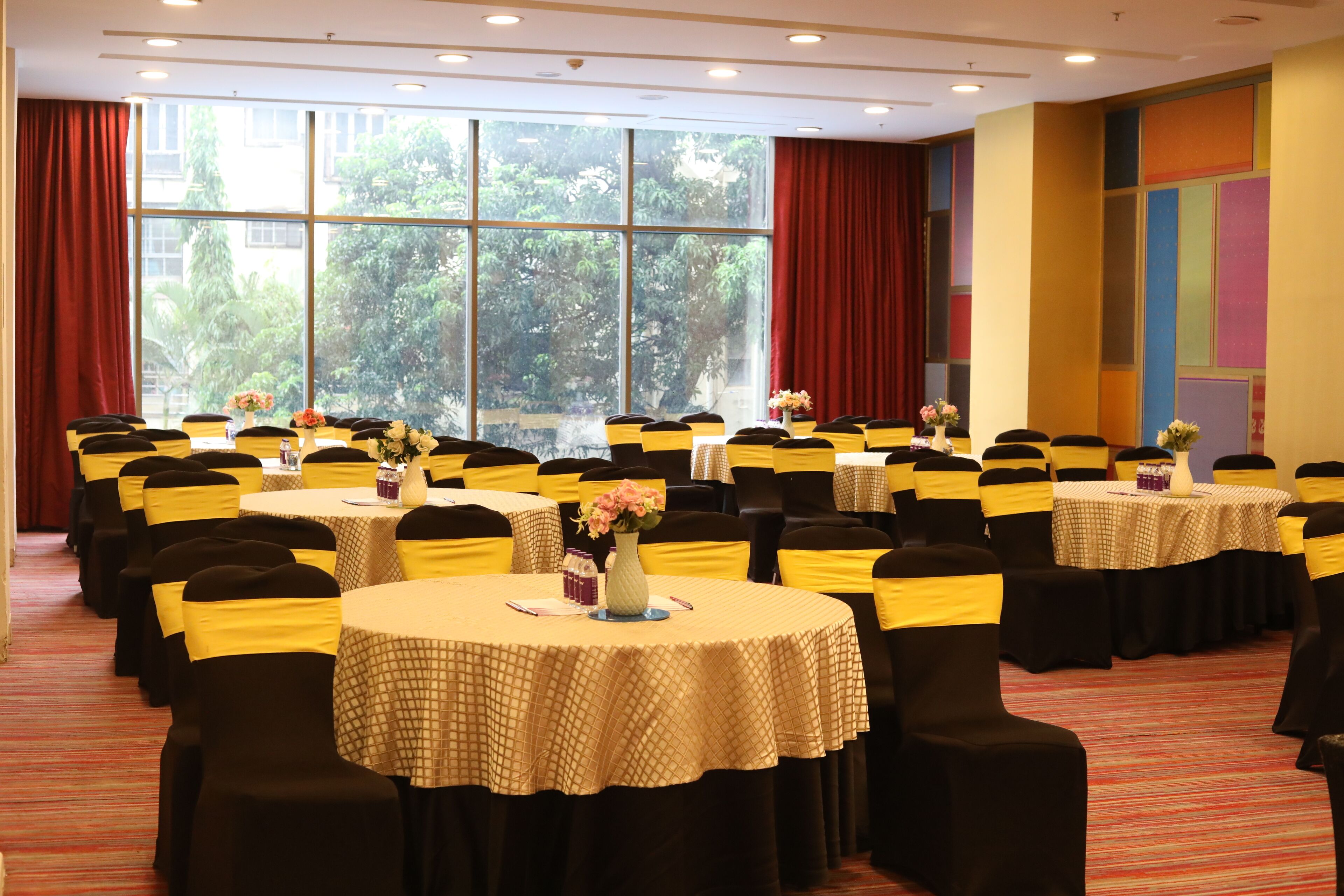 A conference room with multiple round tables, each with a tablecloth and chairs with yellow sashes.
