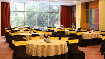 A conference room with multiple round tables, each with a tablecloth and chairs with yellow sashes.