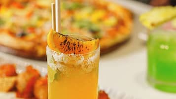 A table with a glass of orange juice, a pizza, and various dishes.